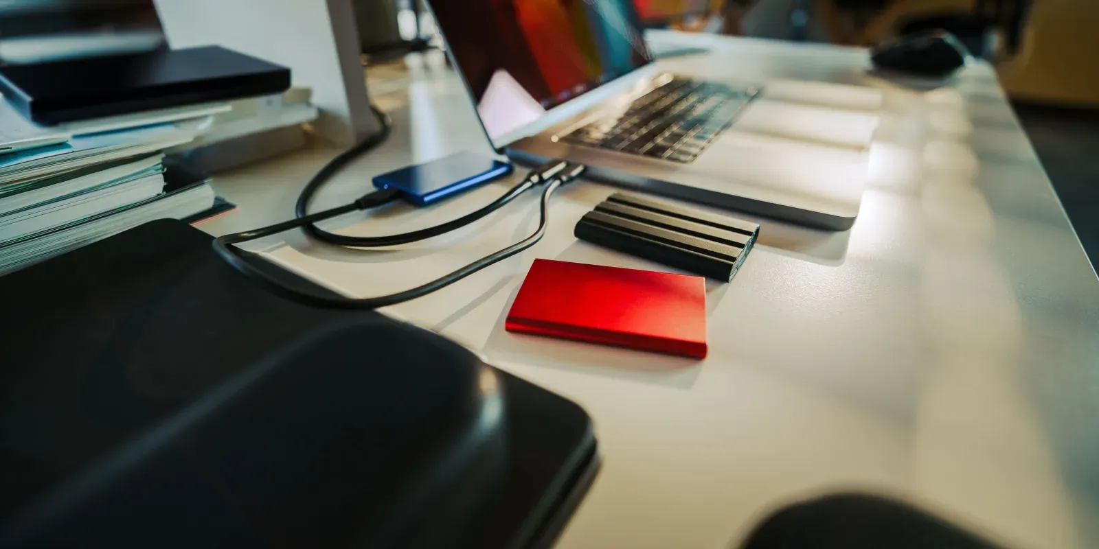 Laptop mit mehreren externen Laufwerken auf einem Schreibtisch als Symbol für mehrere unabhängige Backup-Kopien